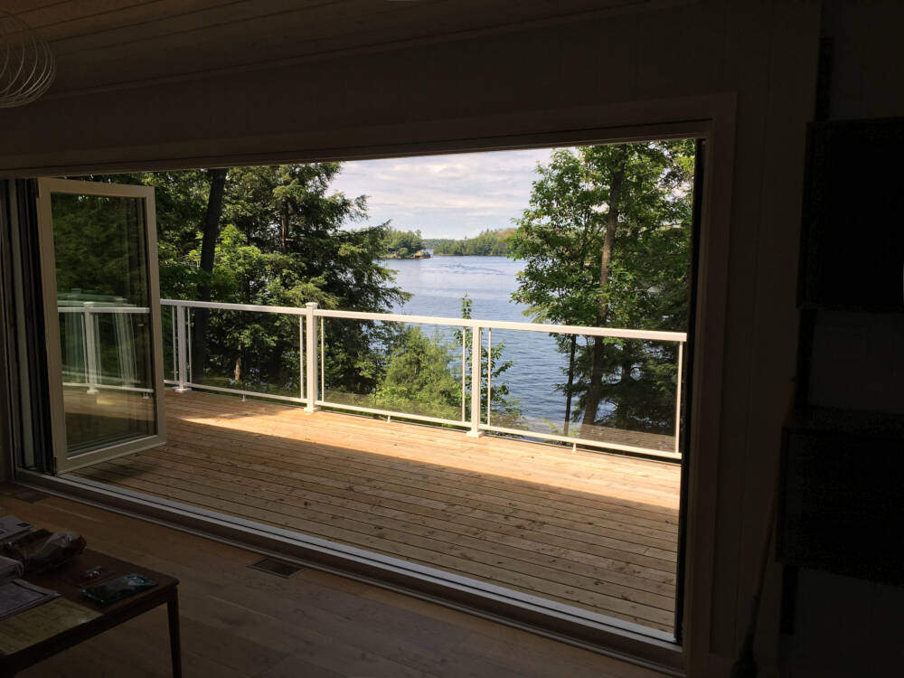 Tree-surrounded view from the 3-Season Porch of a cottage on Lake Muskoka designed by Classic Muskoka Homes.