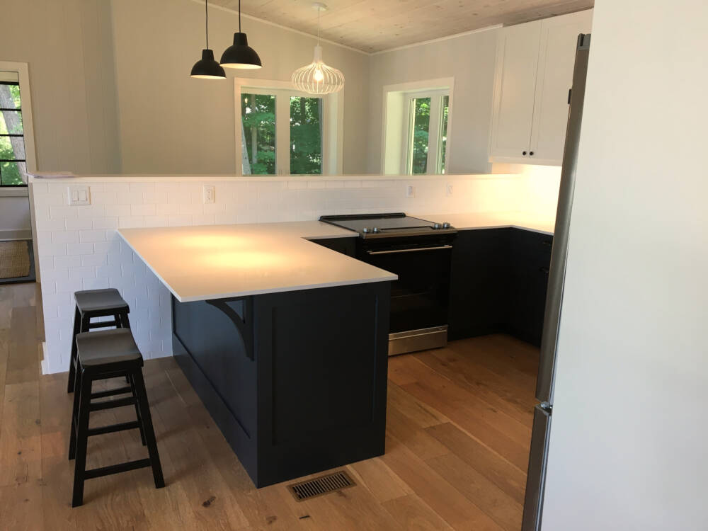 Kitchen interior of cottage on Lake Muskoka showing peninsula countertop and bar stools in casual dining area.