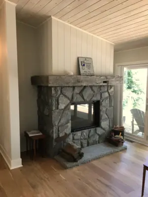 Bright sunlight reflects from the glass fireplace door in a waterfront home in Muskoka.