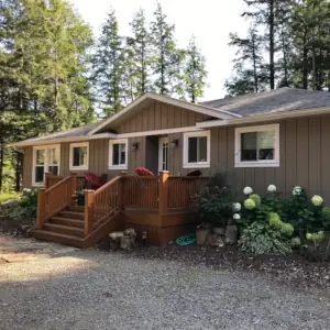 Cedar deck, vertical board and batten siding and white trim come together in the neat appearance of this cottage in the Township of Lake of Bays, Muskoka, Ontario.