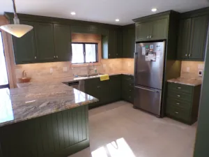 Striking granite countertops reflect sunlight atop bold &ldquo;Weathersffield Moss&rdquo; green kitchen cabinets in this builder's cottage renovation & custom kitchen project in Muskoka.