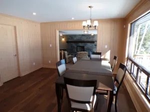 The formal dining room of this Lake of Bays cottage renovation project overlooks both the lake and the masonry fireplace.