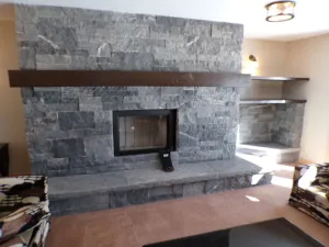 Hand-finished mantel timber of Douglas Fir hangs above a large wood-burning masonry fireplace in this Muskoka cottage.