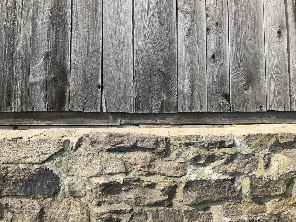 A common finish in custom home designs, rustic weathered barn board, shines silver in the summer sunlight in Muskoka, Ontario.
