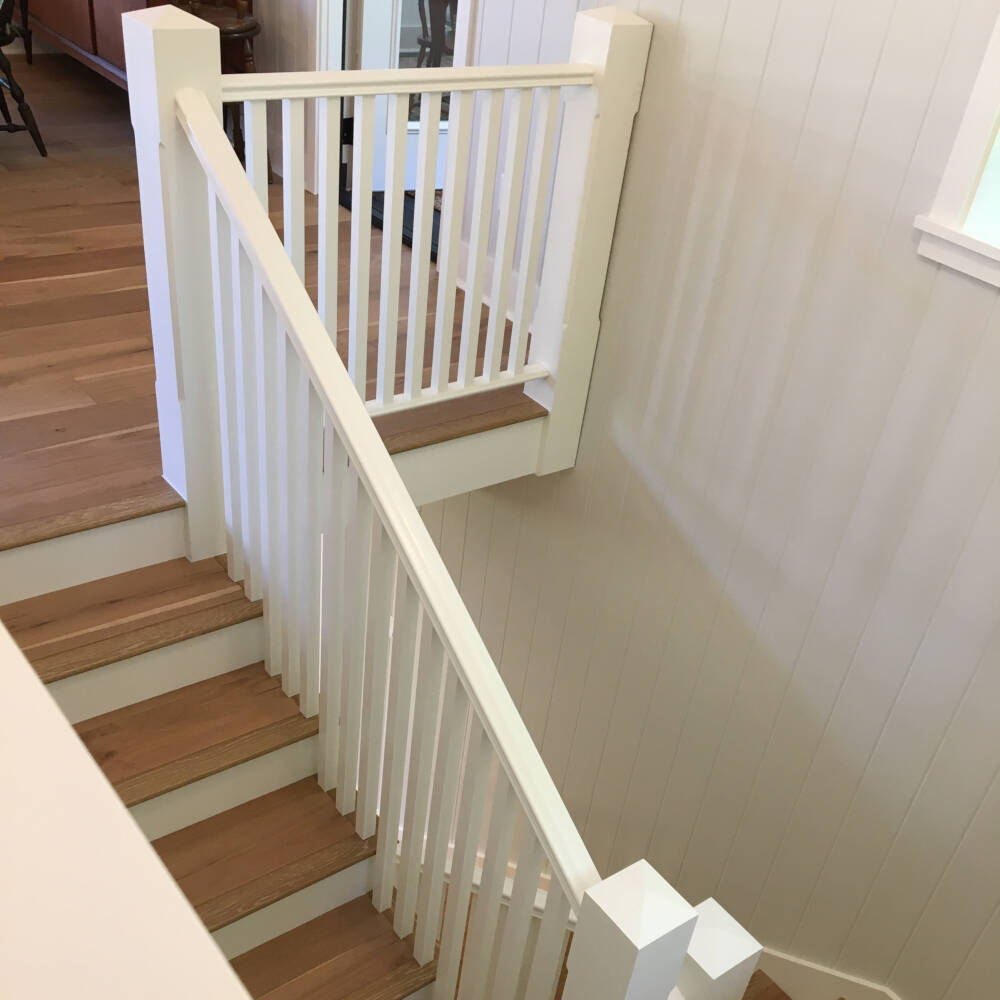 Site-fabricated wood staircase and white newel posts, balustrades and oak handrails in a cottage on Lake Muskoka.