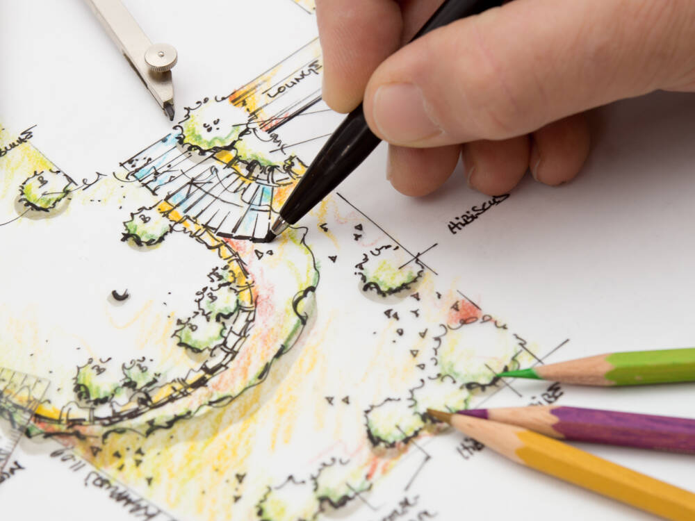 A designer wields a pen in drawing a landscape architecture design drawing.