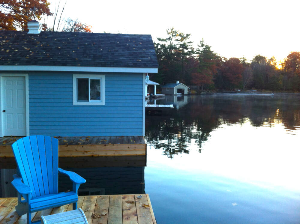 Coloured fall leaves lay across the shingled roof and dock of a boathouse design built on Lake Muskoka.