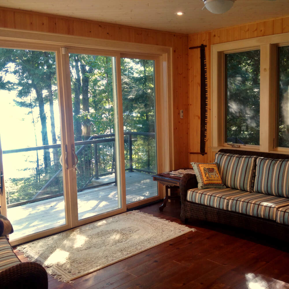 Large double sliding glass patio doors open from the Muskoka Room onto a deck in this cottage design.