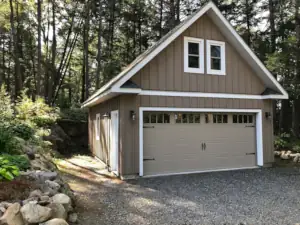 A front view showing the gable roof with partial roof returns, loft windows and surrounding plantings by the garage Owners.