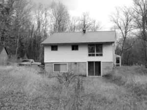 An image shows the existing home on the property prior to demolition and replacement with the new house design.
