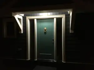 Light emanating from the covred entry soffit illuminates the entry door of this Lake Muskoka home on a dark night.