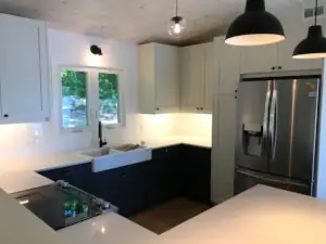 An apron-front farmhouse sink is centred on a window overlooking the yard and driveway of the property.
