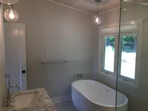The ensuite Master Bath features a tiled, glass-enclosed shower, a freestanding bathing tub and a double vanity cabinet with two lavatory sinks.