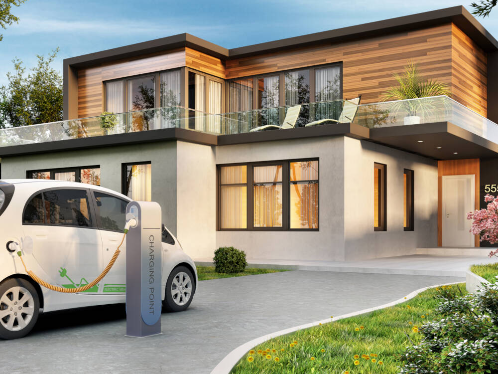 An energy-efficient or Passive House design is pictured with an electric vehicle charging station in the driveway.