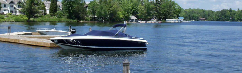 Boats moored in Lake Joseph with sunlight reflected from the lake shimmering on their hulls.