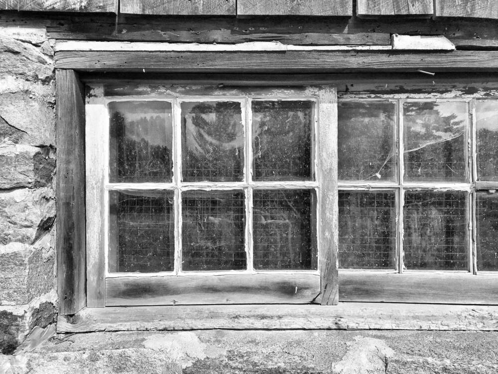 A weathered divided-lite wood window in the stable of a Muskoka barn.